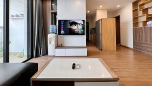 Una sala de estar moderna con televisor, dispensador de agua y ventilador de techo.