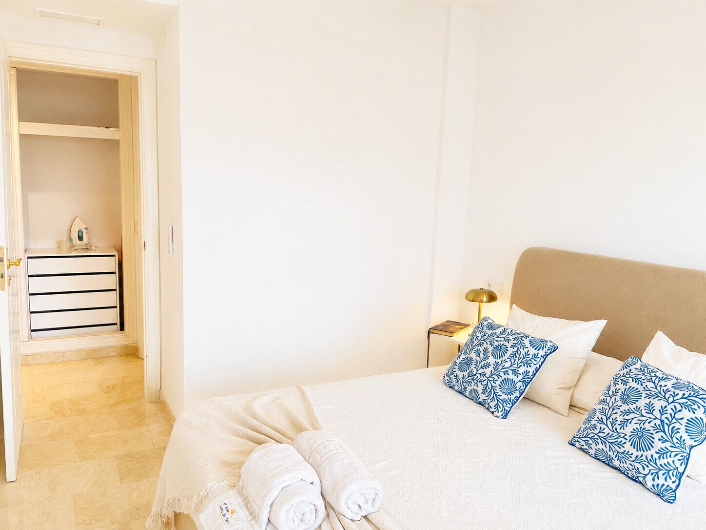 A hotel room with a bed, pillows, a nightstand, and a wardrobe.