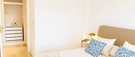 A hotel room with a bed, pillows, a nightstand, and a wardrobe.