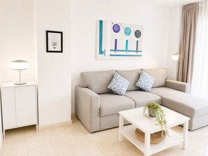 A modern living room with a sofa, a side table, a lamp, a framed certificate, and a wall art piece.
