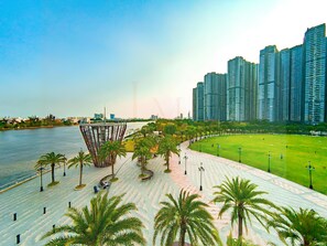 A riverside promenade with a modern bridge, a grassy park area, and high-rise buildings in the background. - Saigon Landmark Riverside Apartment (Ho Chi Minh City)