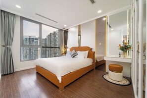 A modern hotel room with a large bed, a small desk, a round stool, and a large mirror. - Saigon Landmark Riverside Apartment (Ho Chi Minh City)