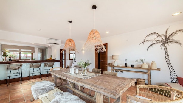 A spacious kitchen with a wooden table, bar stools, and hanging pendant lights. - Stunning home in Llucmajor with private swimming pool, can be inside or outside (Llucmajor)