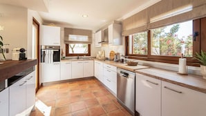 A modern kitchen with white cabinets, a stainless steel dishwasher, and a large window offering a view of the outdoors. - Stunning home in Llucmajor with private swimming pool, can be inside or outside (Llucmajor)