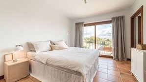 A bedroom with a bed, nightstand, lamp, and a view of the outdoors through a balcony. - Stunning home in Llucmajor with private swimming pool, can be inside or outside (Llucmajor)
