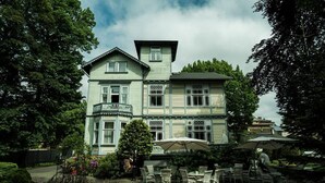 Een groot, twee verdiepingen tellend gebouw met een balkon en een overdekt terras.