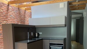 Een kleine keuken met een inbouwoven, een spoelbak en een waterkoker.