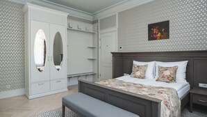 Een slaapkamer met een groot bed, een bankje, een kledingkast en een nachtkastje.