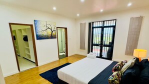 A bedroom with a large bed, a dark-colored sofa, a small table with a lamp, and a painting on the wall. - 3 Bedroom Apartment in Suva (Suva)