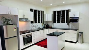 A modern kitchen with white cabinets, a black countertop, and stainless steel appliances. - 3 Bedroom Apartment in Suva (Suva)