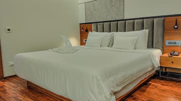 A neatly made bed with a wooden headboard, a bedside table with a phone, and a wall-mounted light fixture.