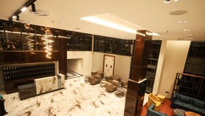 Eine moderne Lobby mit Marmorboden, einer Sitzecke mit Sofas und Sesseln sowie einer großen Holzsäule.