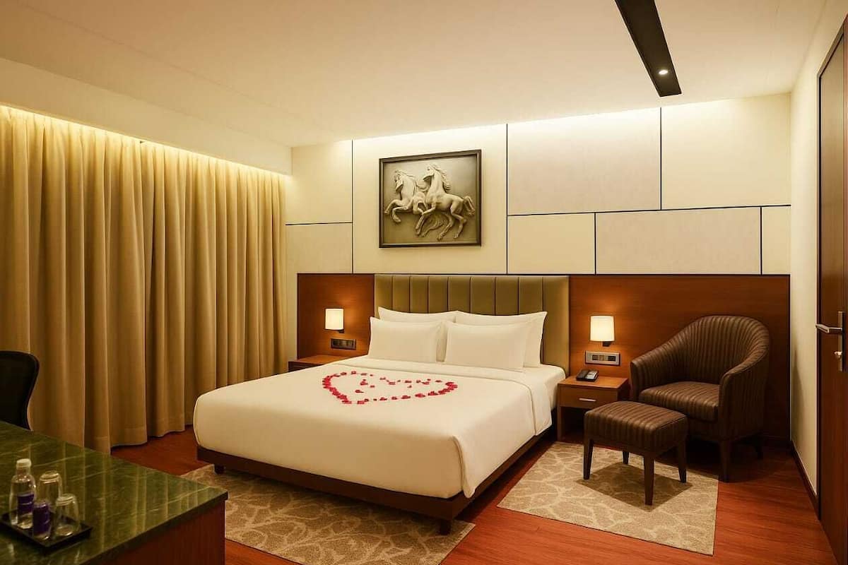 A hotel room with a bed, a chair, a desk, and a painting on the wall.