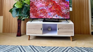 A modern living room with a flat-screen TV on a wooden TV stand, a potted plant, and a patterned rug. - Wonderful One Bedroom at Avida No. 40 (Iloilo)