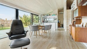 Eine moderne Küche mit einer zentralen Kochinsel, Holzböden und einem Essbereich mit Stühlen und Tisch.