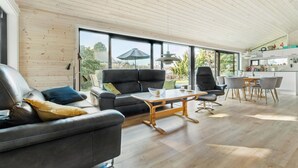 Ein modernes Wohnzimmer mit einer Ledersofa, einem Holztisch und einem Essbereich mit Stühlen und Tisch.