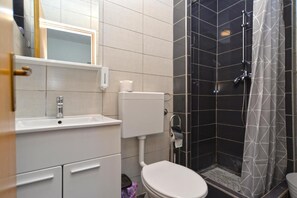 A bathroom with a white sink, toilet, and shower area. - Charming coastal gateway (Fažana)