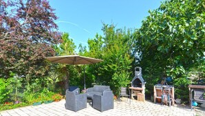 An outdoor patio with a grill, seating area, and a pergola. - Charming coastal gateway (Fažana)