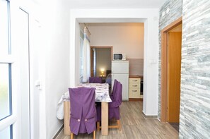 A compact kitchen with a microwave, a small refrigerator, and a dining area with a table and purple chairs. - Charming coastal gateway (Fažana)