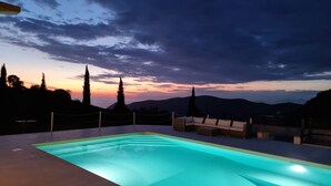 Une piscine offrant une vue sur le coucher de soleil et les montagnes en arrière-plan.