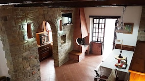 Une cuisine rustique avec une cheminée en briques, des armoires en bois et un sol carrelé.