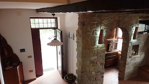 Une cuisine rustique avec des murs en pierre, un meuble en bois et un luminaire suspendu.