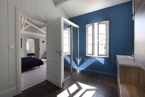 Un dormitorio con cama, un baño con lavamanos y una puerta que da a otra habitación.