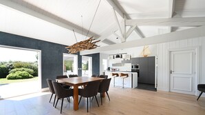 Una cocina amplia con electrodomésticos modernos, un comedor con mesa y sillas de madera, y vistas a un jardín a través de grandes ventanales.