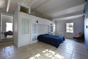 Un dormitorio con cama, una silla, un radiador y una ventana.