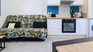 A compact living space with a sofa, kitchenette, and a small dining table.
