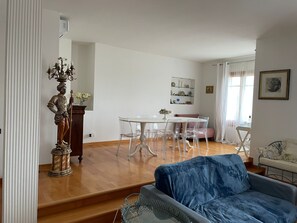 A living room with a blue sofa, a dining table with chairs, a statue, and a staircase. - Spacious Apartment in the Heart of Tuscany (Castelfiorentino)