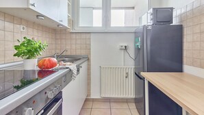 A compact kitchen with a stove, oven, sink, and a small refrigerator. - Rosalia - Stylish living, central experience (Kaiserslautern)