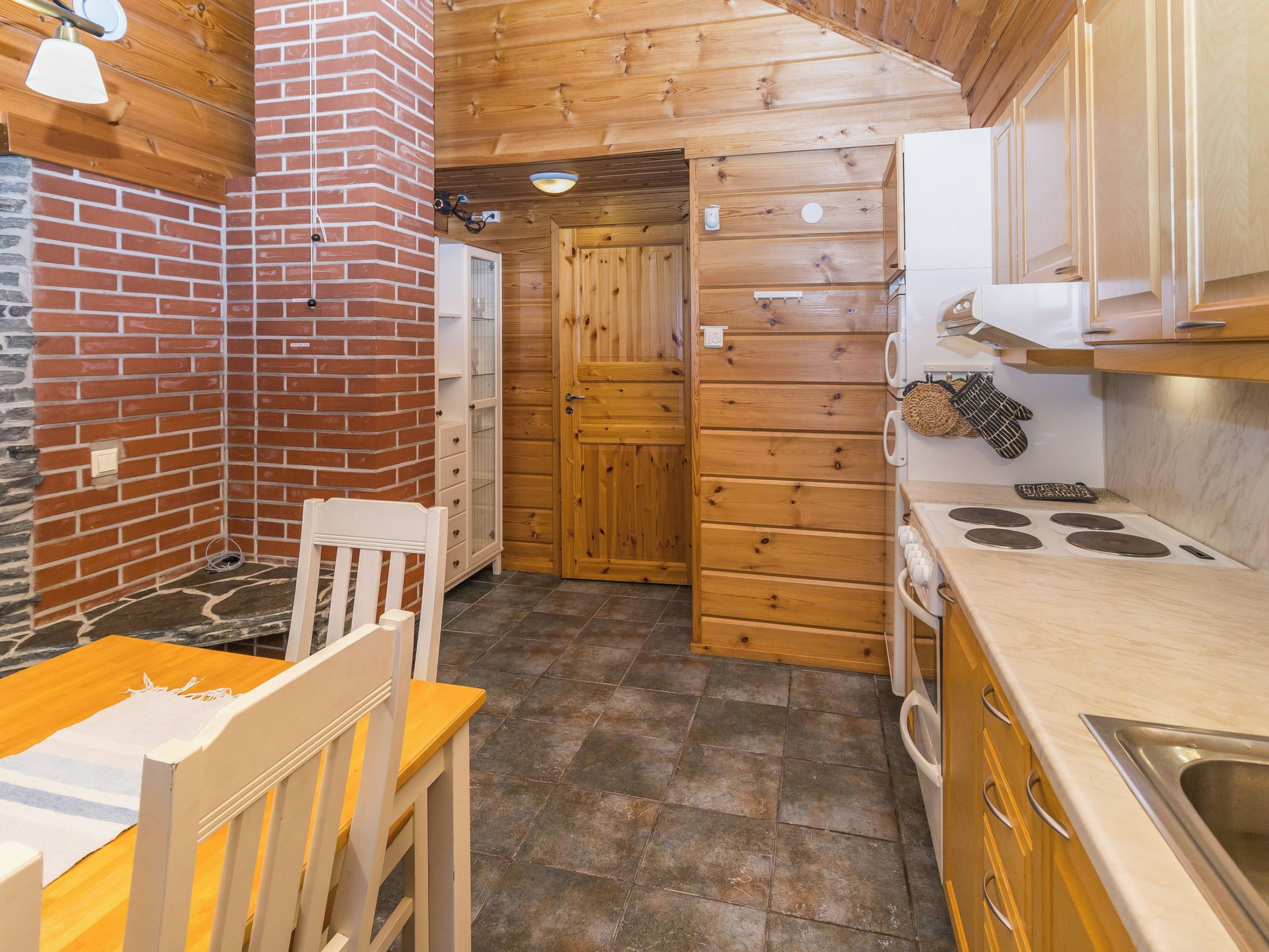 Une cuisine compacte avec des meubles de rangement en bois, une cuisinière et un coin repas comprenant une chaise et une table.