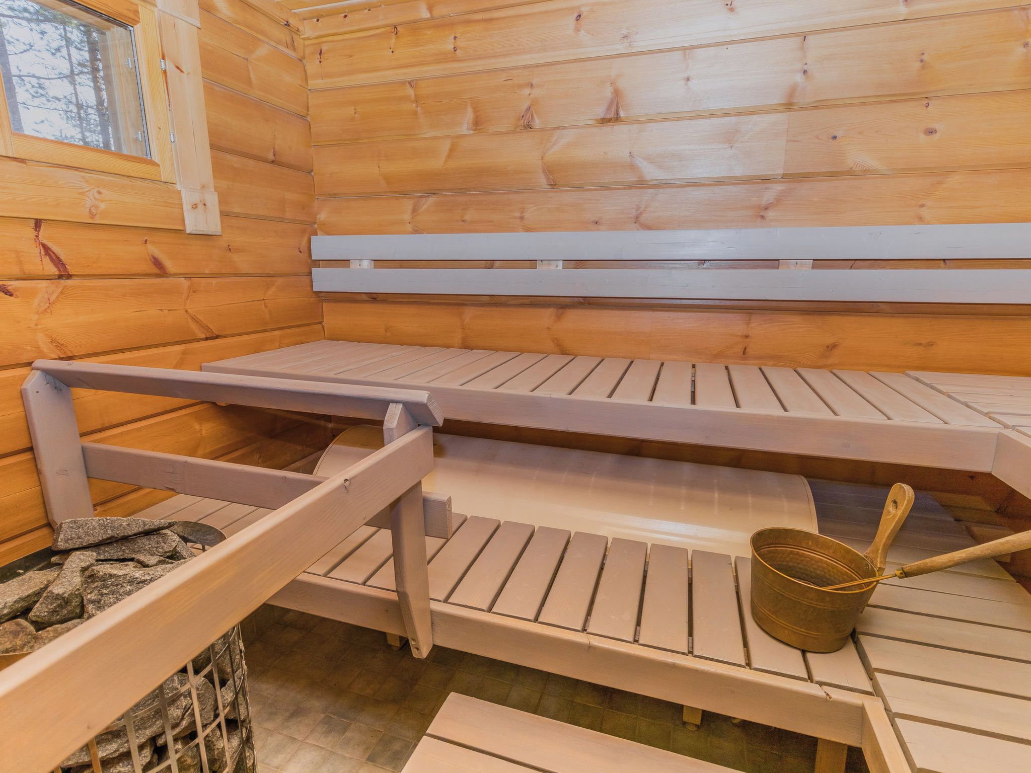 Un sauna avec des bancs en bois et un banc en pierre.