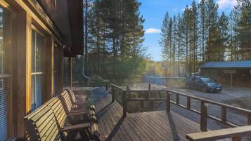 Une terrasse en bois avec des bancs, une vue sur une forêt et un bâtiment en arrière-plan.
