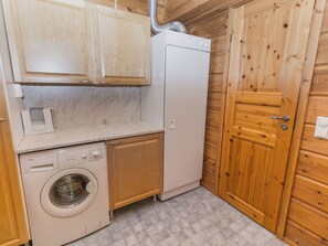 Cocina funcional con lavadora, refrigerador y armarios de madera.