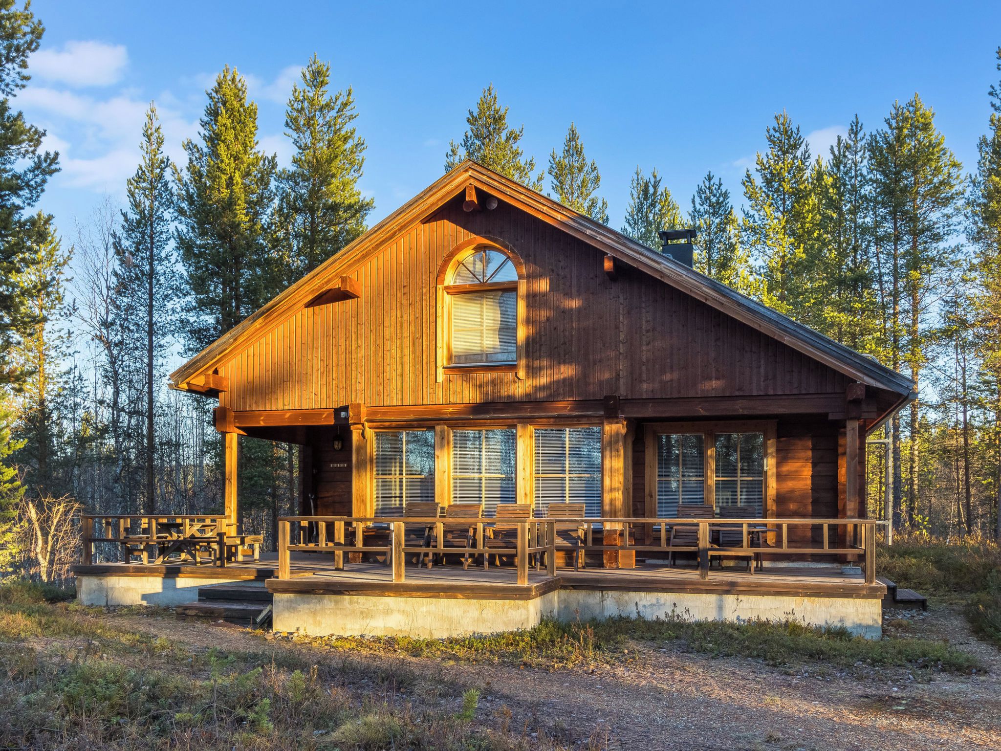 Une cabane en bois avec une véranda, de grandes fenêtres et une cheminée.