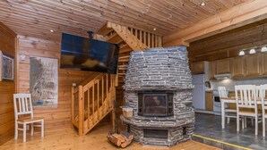 A cozy cabin interior with a stone fireplace, wooden staircase, and a dining area. - Alakoski by Interhome (Inari)
