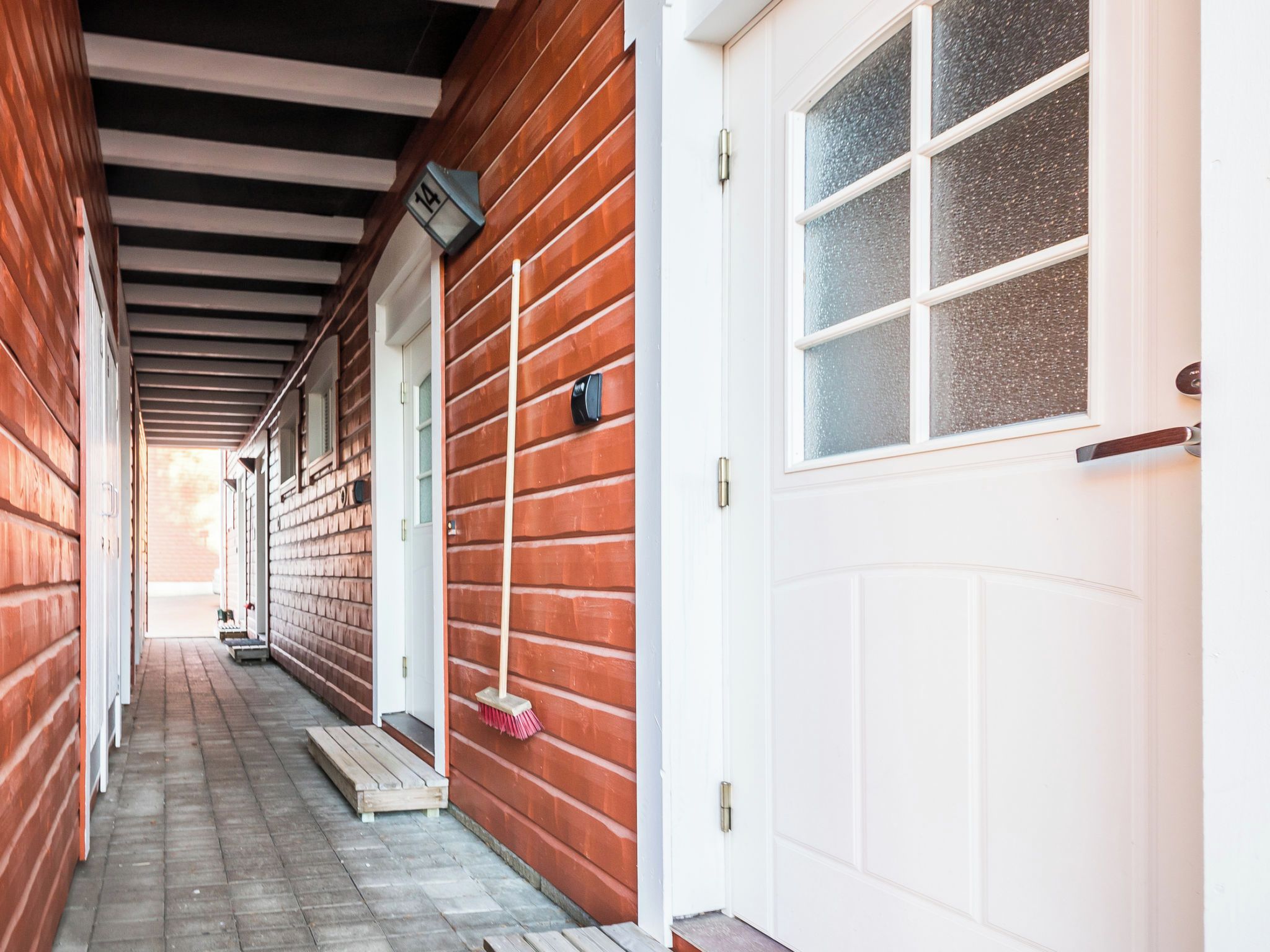 Fachada de madera con una puerta blanca y un ventanal con vidrio texturizado.