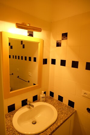 A bathroom with a white sink, a mirror, and black and white tiles.