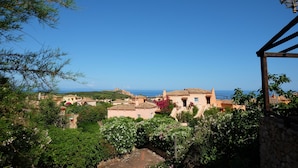 A coastal village with traditional architecture, a stone wall, and a view of the sea.