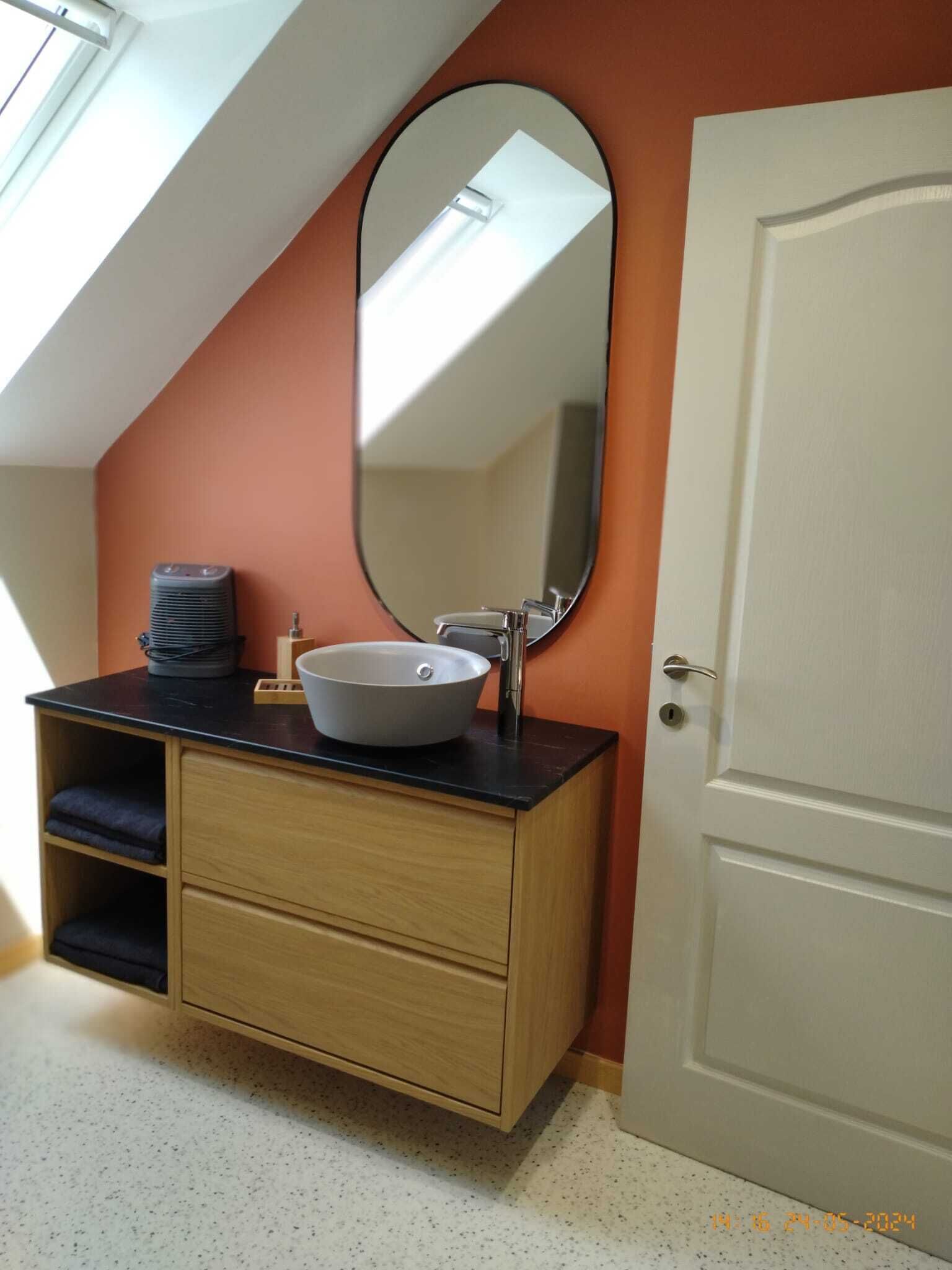 A bathroom with a white sink, a mirror, and a wooden cabinet.