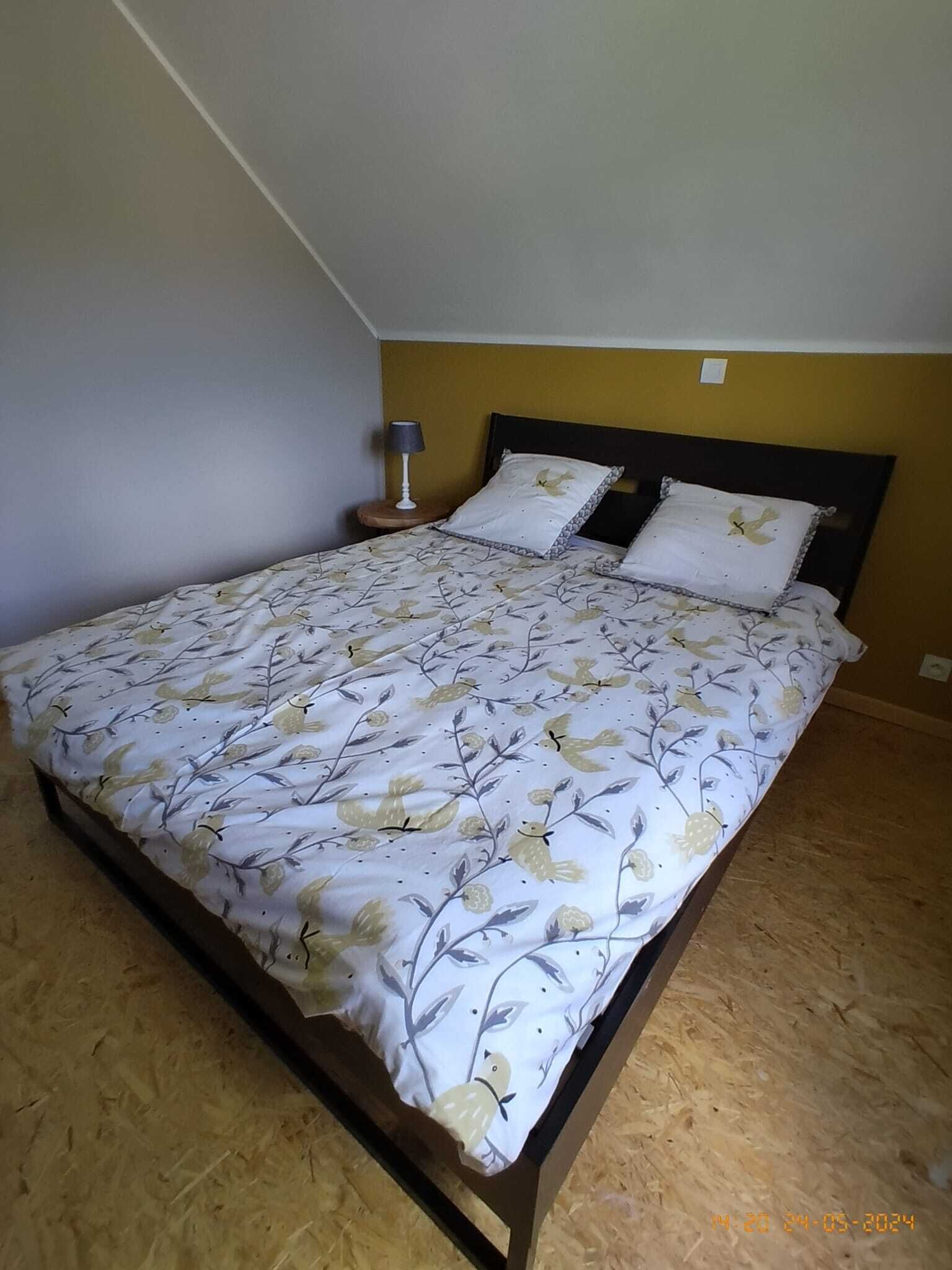 Un letto singolo con una coperta a fiori, un comodino con una lampada e una sveglia a muro.