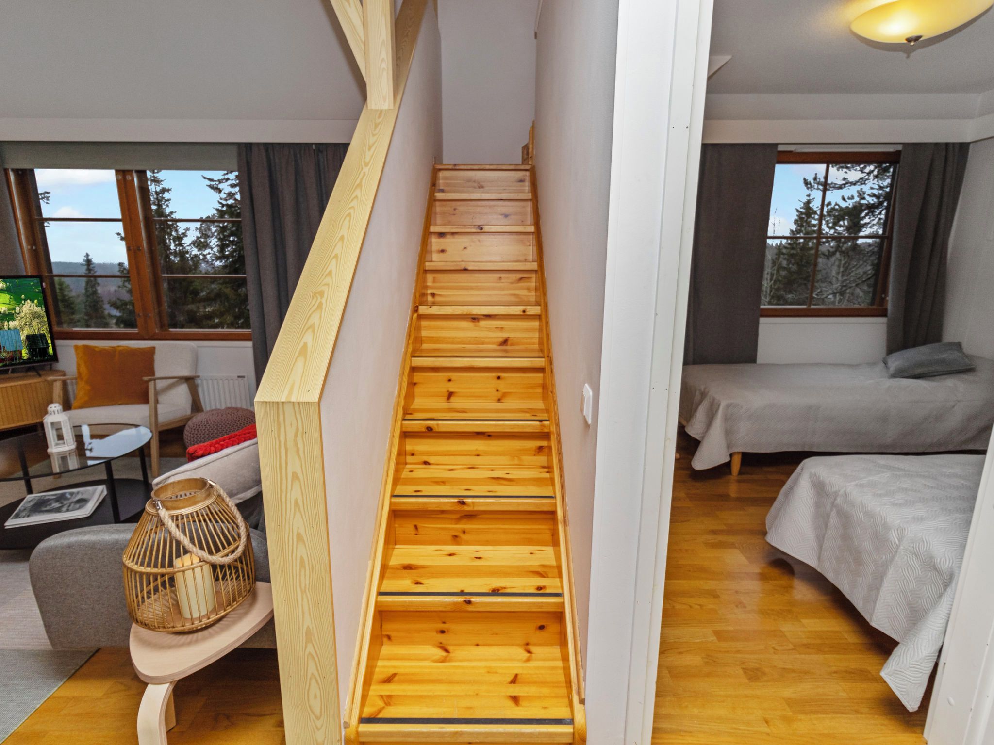 A wooden staircase in a modern room with a bed, a sofa, and a television.