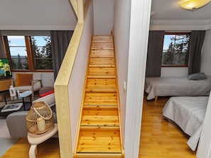 A wooden staircase in a modern room with a bed, a sofa, and a television.