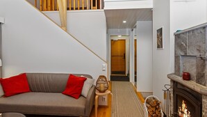 Una sala de estar moderna con un sofá gris, una chimenea y una escalera.