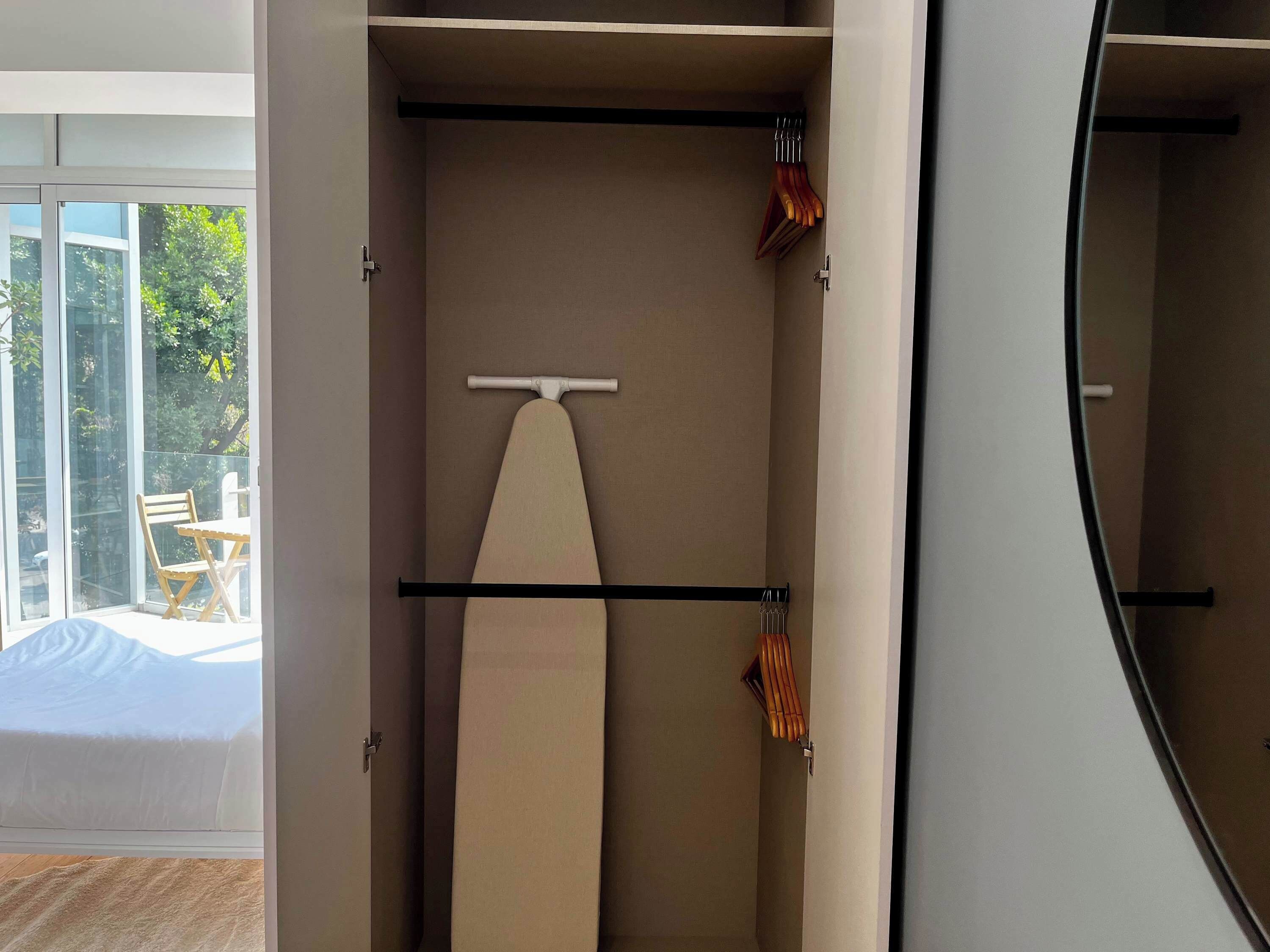 Une chambre moderne dotée d’une grande fenêtre, d’un lit et d’une armoire avec une tringle pour suspendre les vêtements.