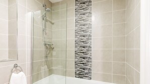 Ein modernes Badezimmer mit einer Duschkabine, einer Badewanne und einer gefliesten Wand mit einem einzigartigen Muster.