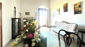 Ein Wohnzimmer mit einer Couch, einem Glastisch, einem Blumenstrauß und einem Kamin.