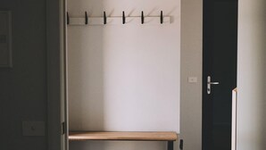 A room with a wooden bench, a coat rack, and a door.